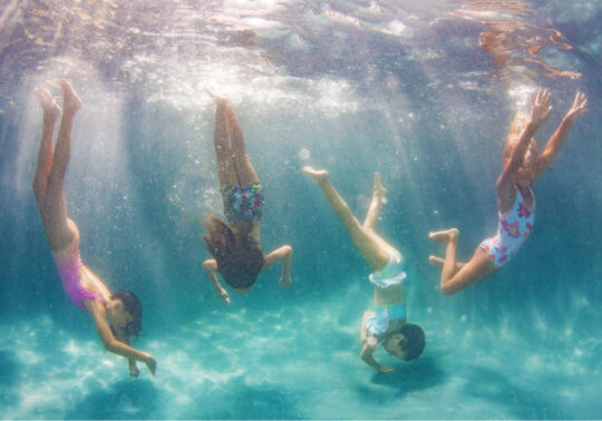From left: Marissa wears pink Chloé one-piece; Kate wears Molo bikini top and shorts; Maddie wears ruffled Billieblush suit; Aurora wears floral one-piece by Submarine.