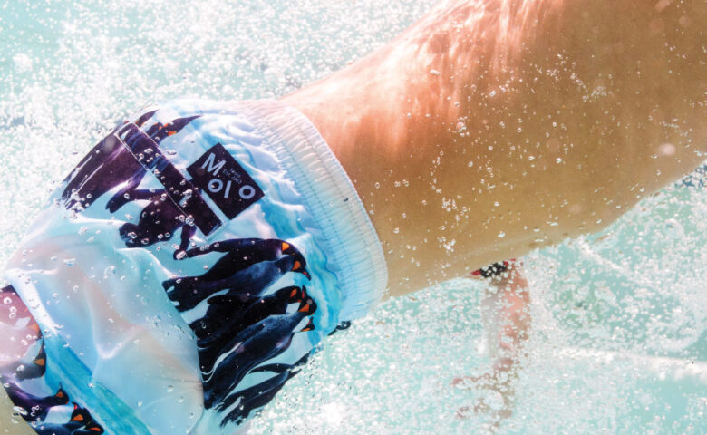 George wears Molo penguin boardshorts.