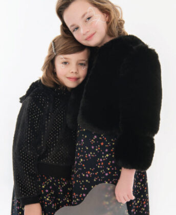 (from left to right): Layla wears Appaman black faux fur hooded pullover with black star print skirt by Molo; Peyton wears Imoga black faux fur jacket with Molo star print skirt.