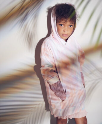 Laniya wears Lazypants tie-dye hoodie with Mayoral sweater and pleated shorts.