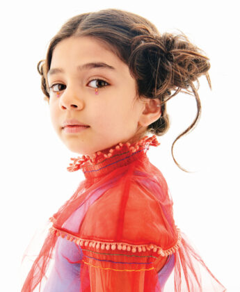 Samsara wears Pink Chicken dress underneath coral blouse by Tia Cibani.